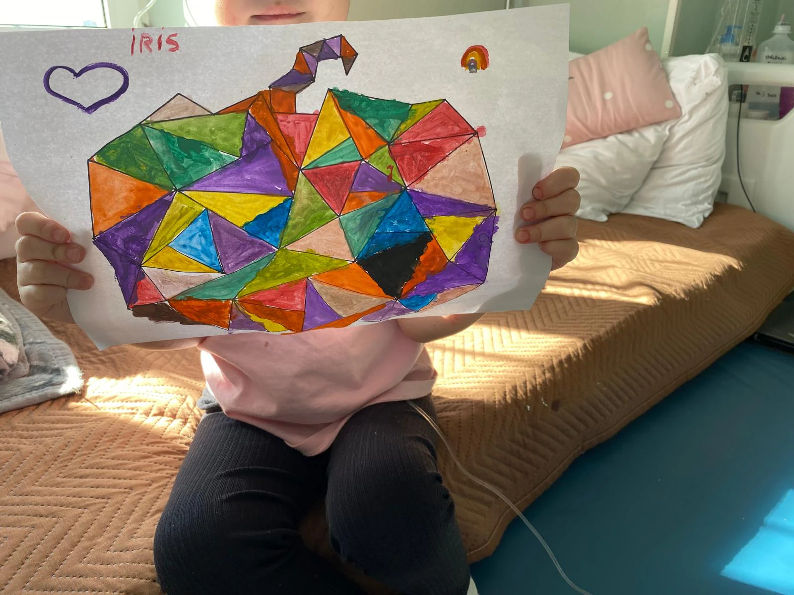 Un copil ține în mâini un mozaic din hârtie colorată