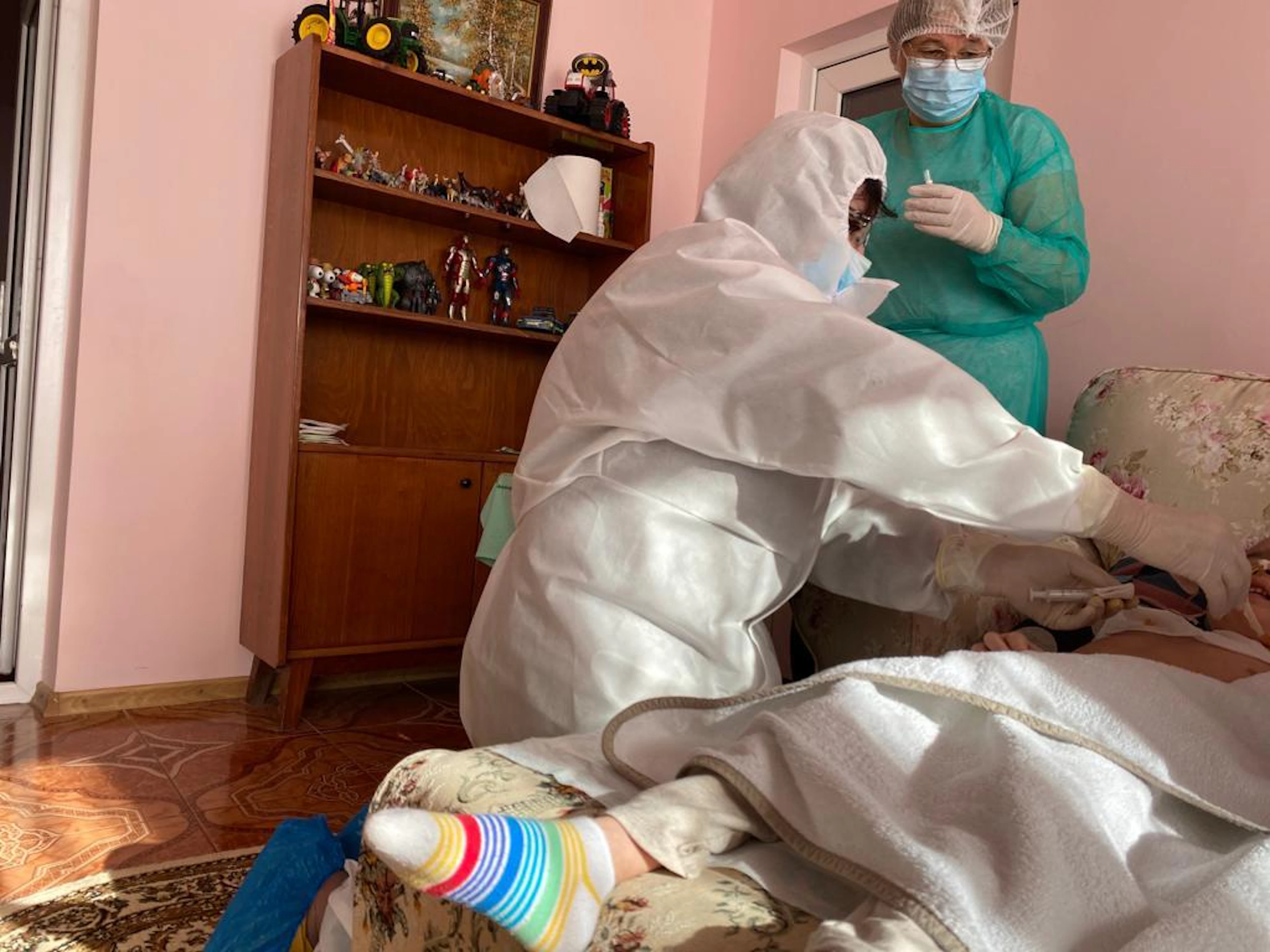 Membru al echipei medicale examinează un copil în camera lui